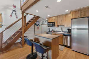 Kitchen featuring a center island, a sink, light wood-type flooring, recessed lighting, and appliances with stainless steel finishes