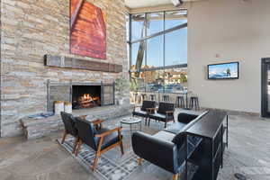 Living room with stone tile floors, a high ceiling, and a fireplace