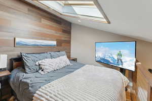 Bedroom featuring recessed lighting, wooden walls, and vaulted ceiling with skylight