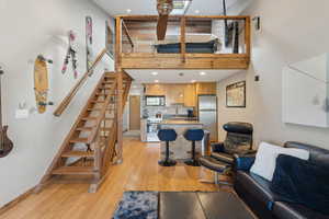 Living area with stairs, a towering ceiling, light wood finished floors, baseboards, and recessed lighting