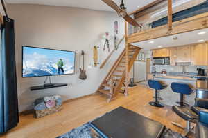 Living room featuring a ceiling fan, baseboards, light wood-style floors, and stairway
