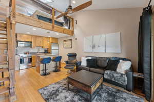 Living room with a ceiling fan, a towering ceiling, recessed lighting, and light wood-style floors