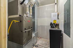 Utility room featuring electric panel and heating unit