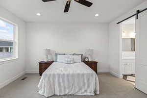 Bedroom with a barn door, baseboards, visible vents, and light colored carpet