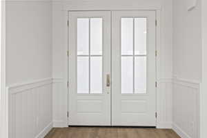 Entryway featuring wainscoting, wood finished floors, and a decorative wall