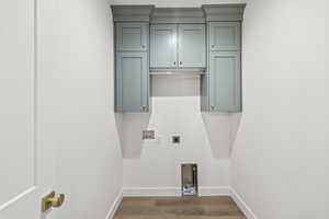 Laundry area with wood finished floors, hookup for a washing machine, electric dryer hookup, cabinet space, and baseboards