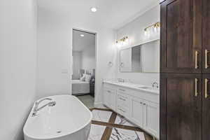 Full bathroom featuring a sink, a soaking tub, double vanity, ensuite bath, and recessed lighting