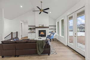 Living area with recessed lighting, a ceiling fan, light wood-style floors, a glass covered fireplace, and high vaulted ceiling