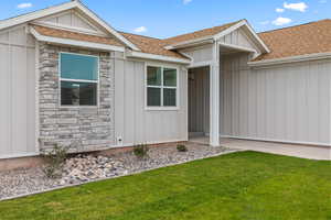 Property entrance featuring board and batten siding, stone siding, and a shingled roof