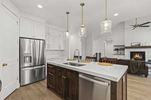 Kitchen with light wood-style flooring, appliances with stainless steel finishes, white cabinetry, and a sink