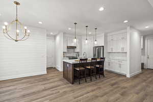 Kitchen featuring light countertops, decorative backsplash, appliances with stainless steel finishes, and white cabinetry