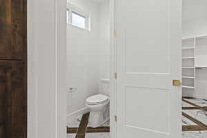 Bathroom featuring marble finish floor, toilet, and baseboards