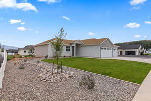 Ranch-style home featuring board and batten siding, a front yard, driveway, a garage, and a mountain view