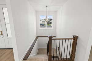 Stairway featuring wood finished floors, baseboards, and an inviting chandelier