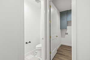 Bathroom with baseboards, wood finished floors, visible vents, and toilet