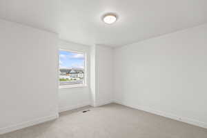 Unfurnished room featuring visible vents, baseboards, and light carpet