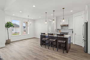 Dining room with baseboards, wood finished floors, recessed lighting, and a notable chandelier