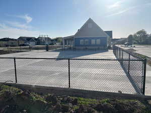 View of tennis court featuring community basketball court and fence