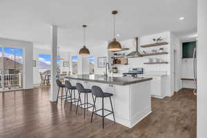Custom Kitchen featuring large island & custom countertops, open shelves, exhaust hood, and white cabinetry.