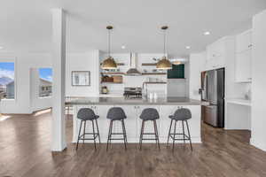 Custom Kitchen featuring large island & custom countertops, open shelves, exhaust hood, and white cabinetry.