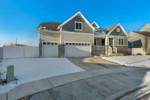 Craftsman-style home with a gate, driveway, stone siding, fence, and a garage