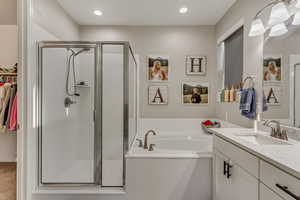 Bathroom featuring a bath, vanity, a shower stall, and a walk in closet