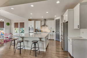 Kitchen with stainless steel appliances, a sink, a kitchen bar, and wall chimney range hood