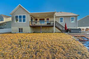 Back of property featuring stairs, fence, a yard, stucco siding, and a hot tub