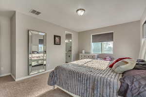 Carpeted bedroom featuring baseboards, ensuite bathroom, and visible vents