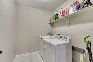 Laundry area with separate washer and dryer, baseboards, marble finish floor, and laundry area