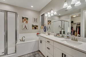 Bathroom with a chandelier, a garden tub, a stall shower, and a sink