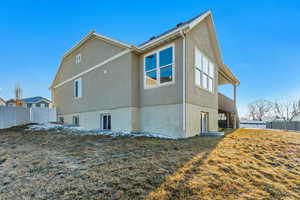 Rear view of property featuring fence, stairway, and stucco siding