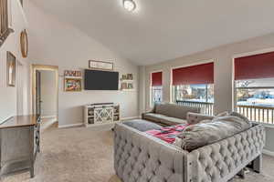 Carpeted living area with vaulted ceiling, a healthy amount of sunlight, and baseboards