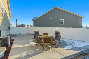 View of patio with a fenced backyard, outdoor dining space, a gate, and central AC