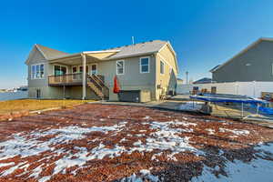 Snow covered property featuring stucco siding, a fenced backyard, stairs, and a patio