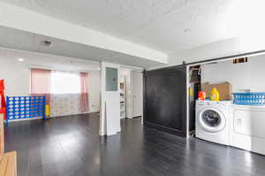 Laundry area featuring wood finished floors, a textured ceiling, laundry area, and visible vents