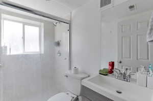Full bathroom with a shower stall, a wealth of natural light, toilet, and visible vents