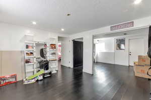 Interior space featuring a textured ceiling, a barn door, baseboards, recessed lighting, and wood finished floors