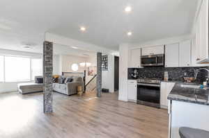 Kitchen with tasteful backsplash, a sink, open floor plan, white cabinets, and appliances with stainless steel finishes