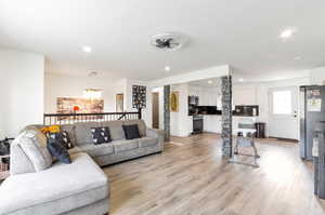 Living area with light wood-type flooring and recessed lighting
