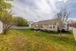 Rear view of house featuring central AC unit, a fenced backyard, entry steps, a patio, and a lawn
