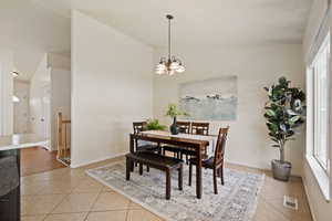 Dining area with a wealth of natural light, a notable chandelier, visible vents, and light tile patterned floors