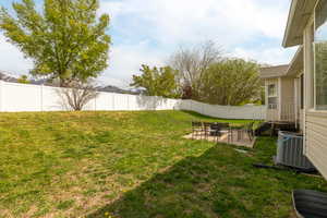 View of yard featuring cooling unit, a fenced backyard, and a patio