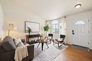 Living area featuring lofted ceiling, hardwood / wood-style floors, and baseboards