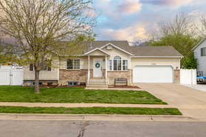 View of front facade with a gate, a garage, driveway, fence, and a front yard