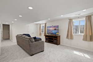 Living area featuring baseboards, light carpet, visible vents, and recessed lighting