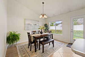 Dining area with a chandelier, high vaulted ceiling, baseboards, and light tile patterned floors