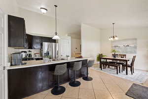 Kitchen with decorative light fixtures, a peninsula, stainless steel fridge with ice dispenser, and light countertops