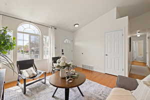 Living room featuring wood finished floors, baseboards, vaulted ceiling, and visible vents