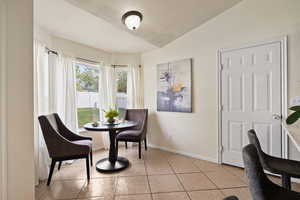 Sitting room featuring vaulted ceiling, baseboards, and light tile patterned floors